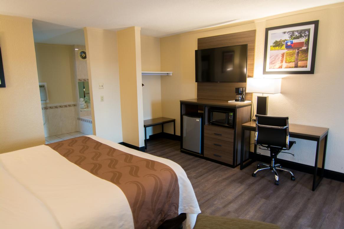 Quality Inn & Suites - Guest Bedroom With One King Bed And Jacuzzi Tub.